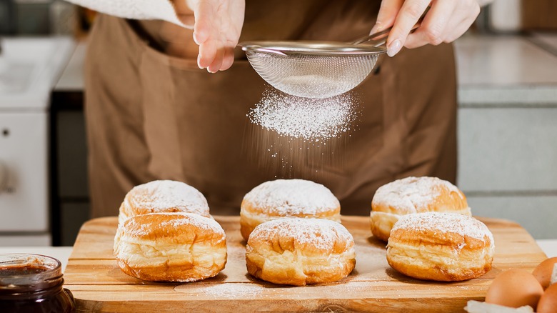 Person coating donuts with sugar