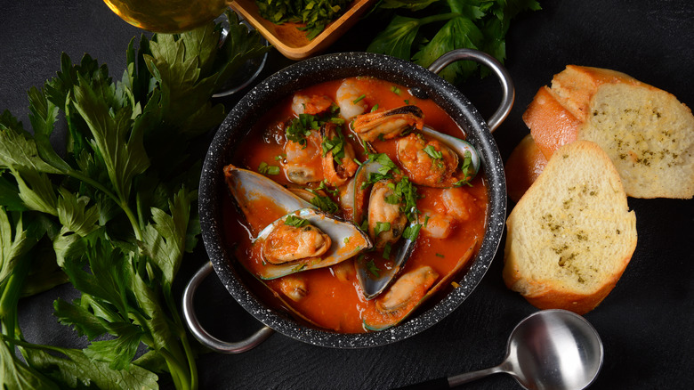 Bouillabaisse in a black bowl with toast