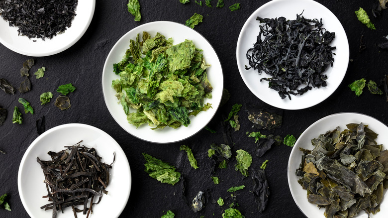 bowls of dry seaweed and sea vegetables on a black surface