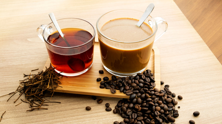 a cup of tea and coffee with tea leaves and coffee beans on a wooden surface