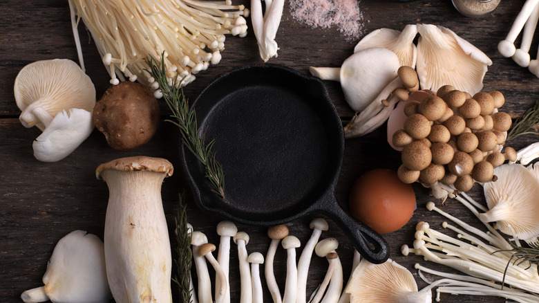 cast iron skillet in the center of various types of mushrooms