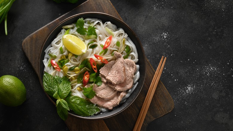 pho with fresh herbs and chopsticks