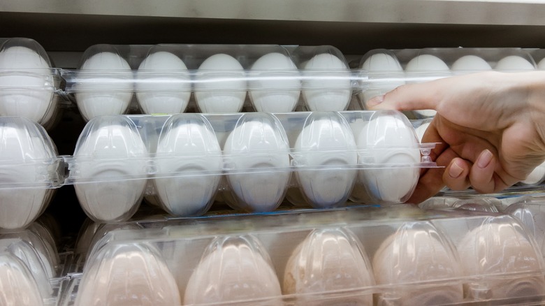 hand grabbing white eggs package