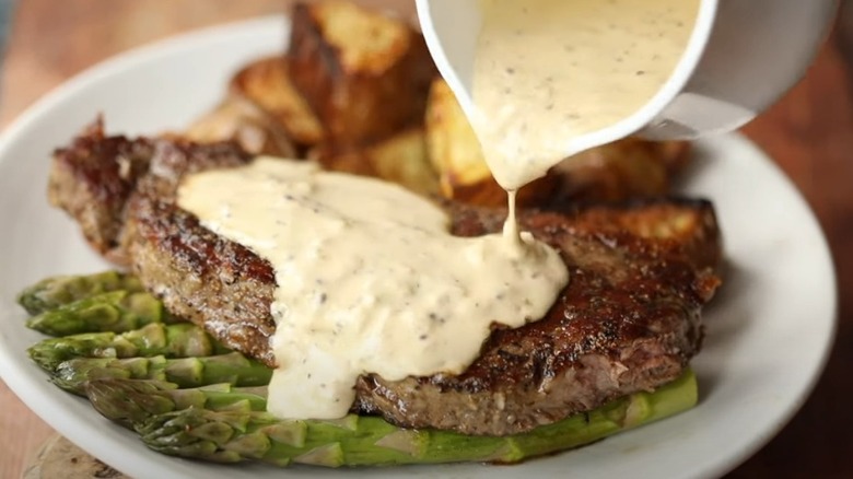 pouring whisky sauce on steak