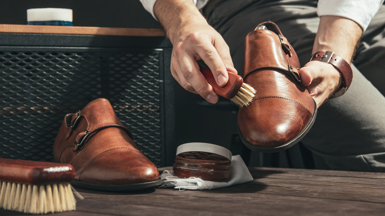 man polishing shoes with brush