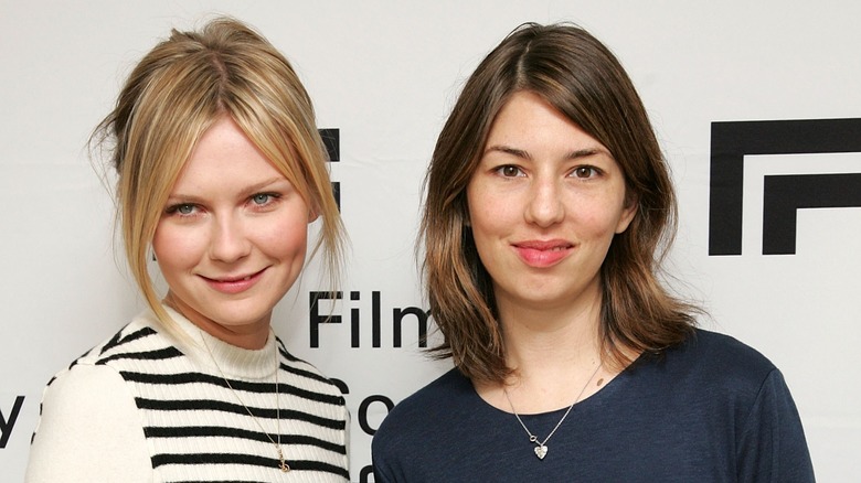 Kirsten Dunst and Sofia Coppola with slight smiles on step and repeat