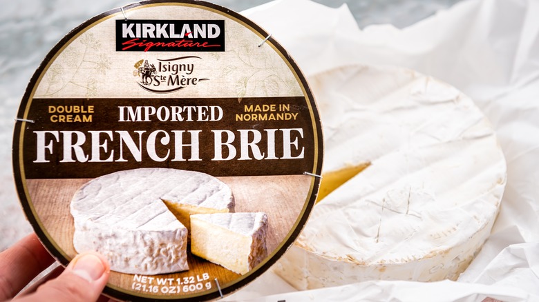 Hand holding Kirkland imported brie package