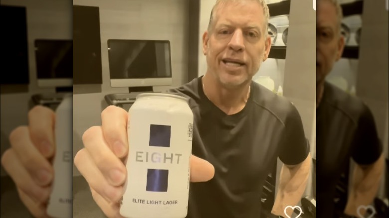 Troy Aikman holding up a can of his new beer Eight