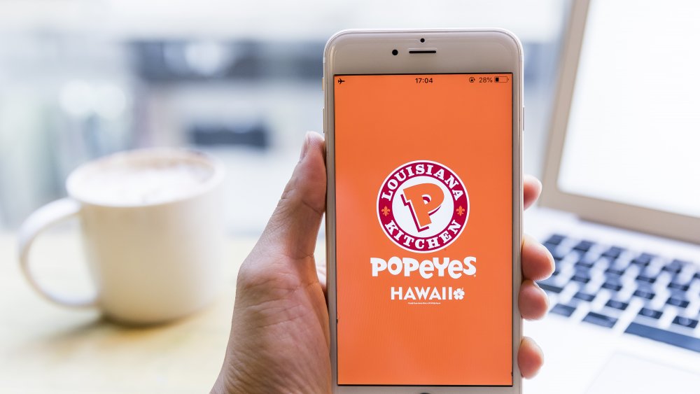 person holding smartphone with Popeyes app open
