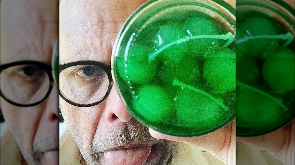 Alton Brown holding a jar of green maraschino cherries