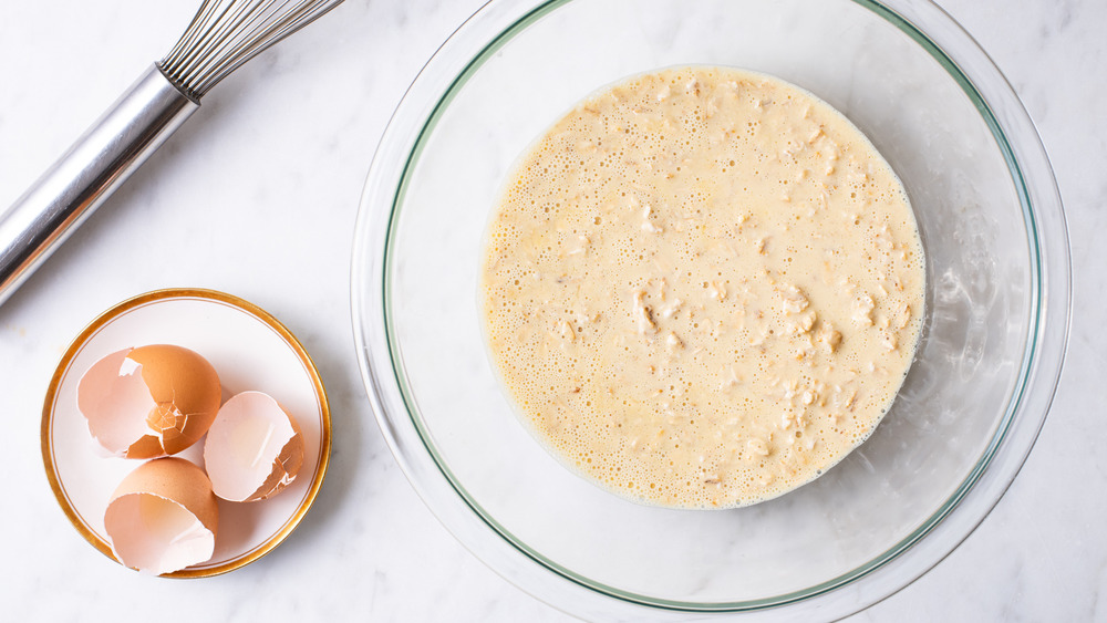 A bowl of pancake batter next to a whisk