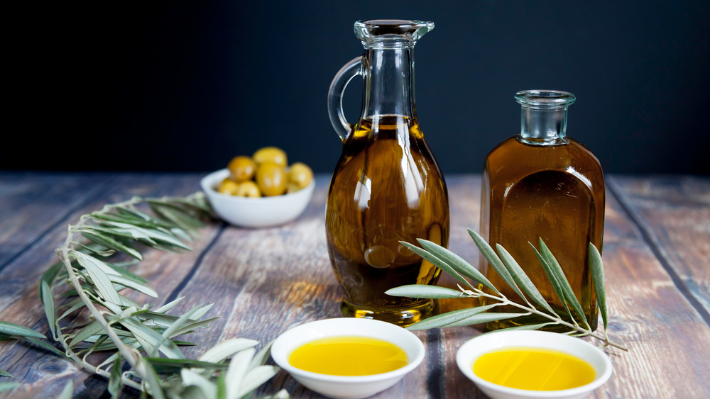 bottles of olive oil on table with bowls of olive oil