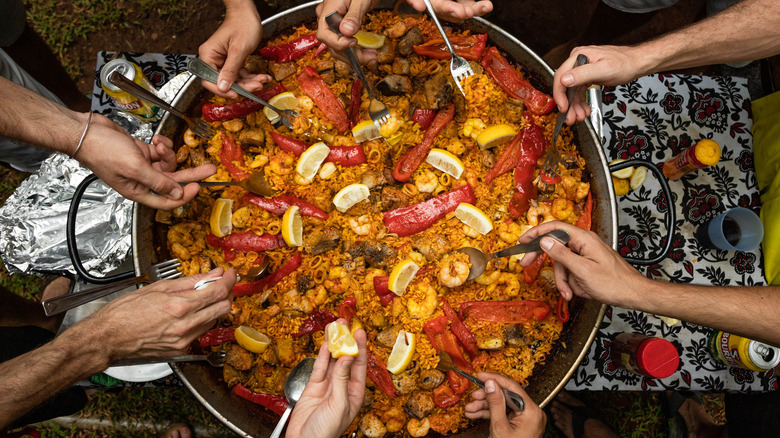 People sharing from pot of paella