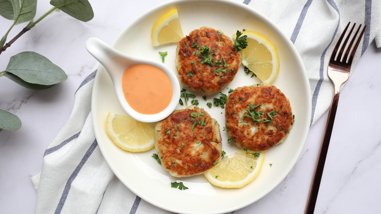 Lobster shrimp cakes with remoulade sauce and lemon on white plate