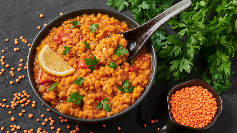 Red lentils in black bowl on dark slate table