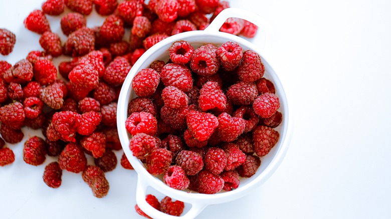 Raspberries in bowl and spilling