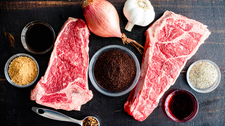 raw strip steaks on a cutting board with coffee shallot and garlic