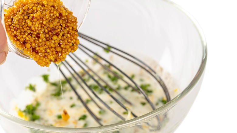 glass bowl of yogurt marinade with mustard seed and whisk