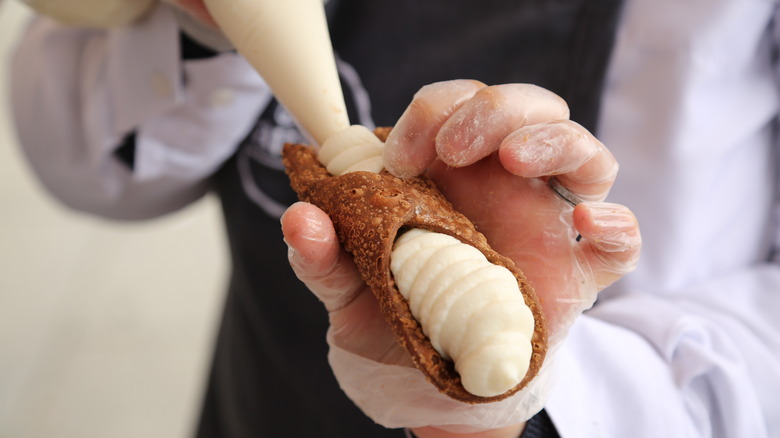 Cannoli being filled with sweet vanilla ricotta