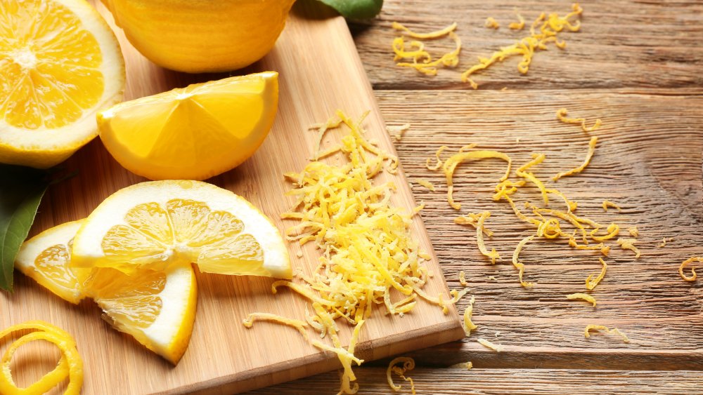 wooden cutting board with sliced lemons and lemon zest