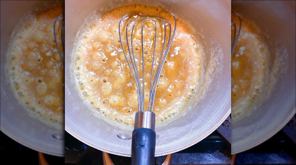 A flat whisk being used to beat eggs