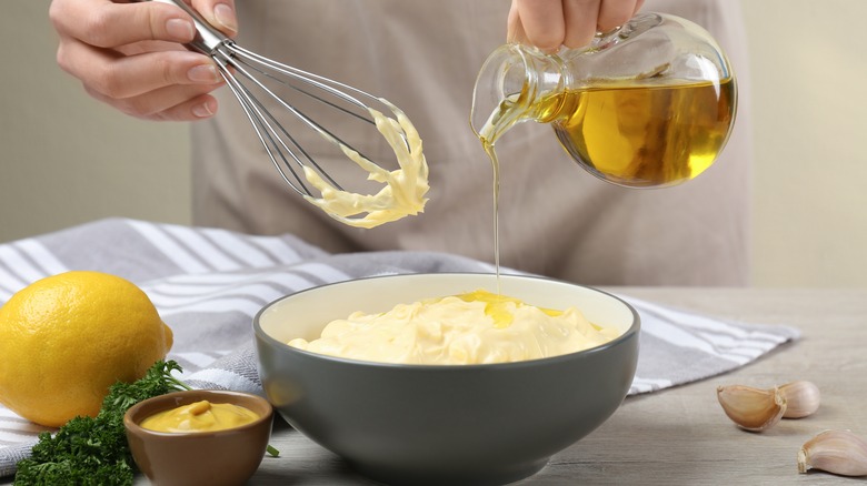 person with whisk, oil, lemon, and mustard making mayo