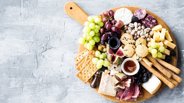 wooden cheese board with fruits and cheese