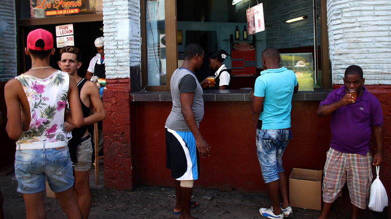 Cubans wait around a cafe