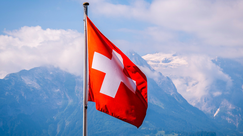 Swiss flag waving before mountains