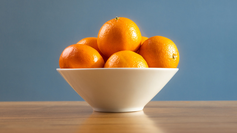 White bowl of oranges on table