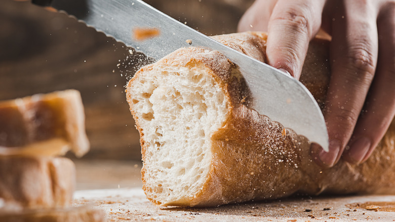 hands slicing bread with serrated knife