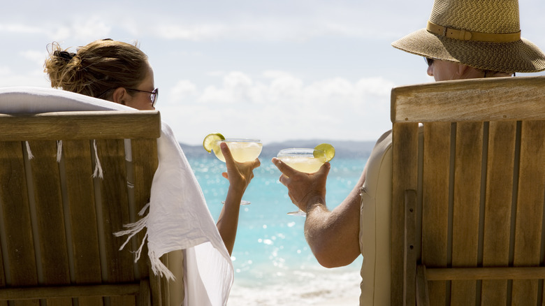 Man and women sitting on beach making a toast with margaritas
