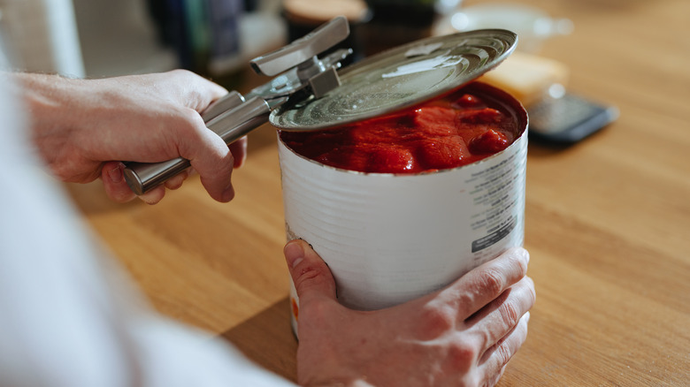 Person opening can of tomatoes