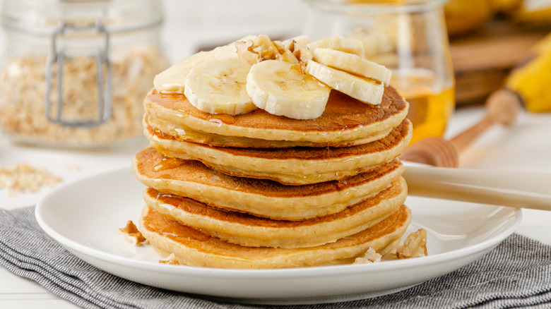 A tall stack of pancakes topped with sliced banana