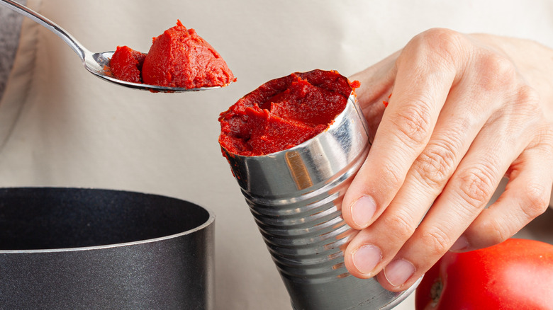 Person scooping canned tomato paste