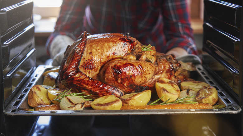 person removing turkey from oven