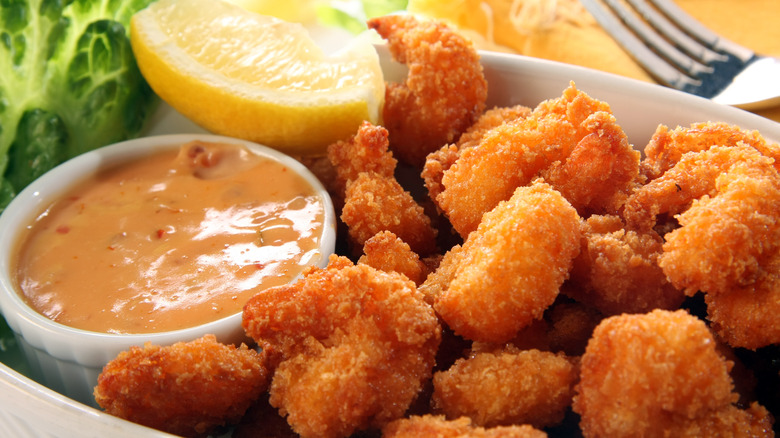 plate of popcorn shrimp with lemon wedge and dipping sauce