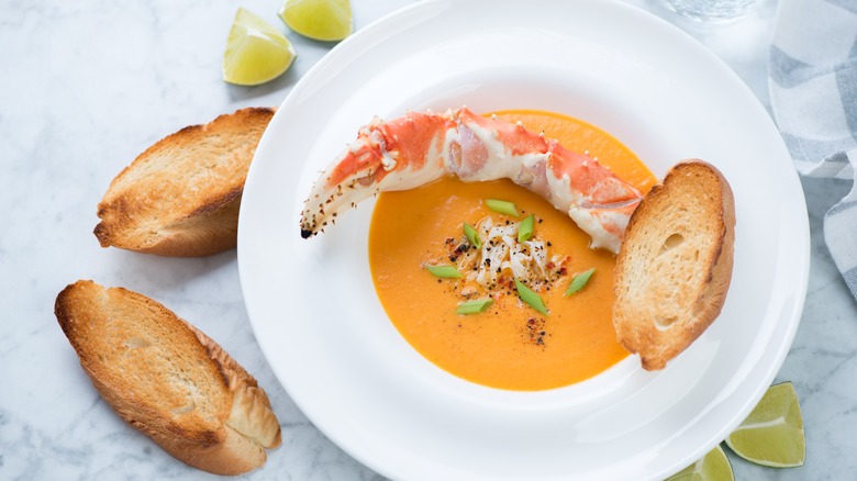 Bowl of bisque soup with crab leg and bread