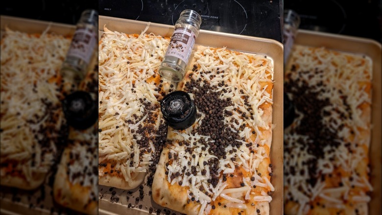 Peppercorns spilled on an uncooked pizza