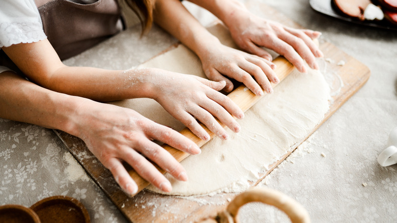 Hands rolling white dough