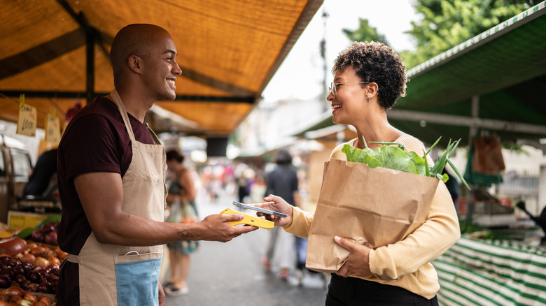 Woman buys veggies at market