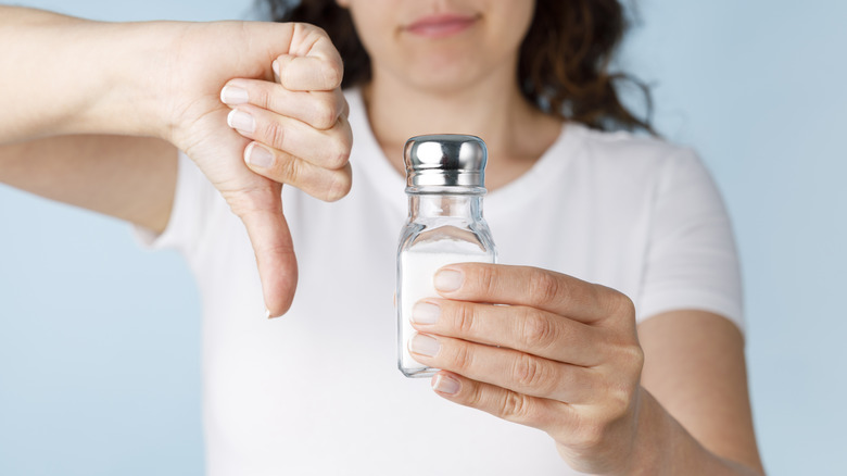 holding salt shaker giving a thumbs down