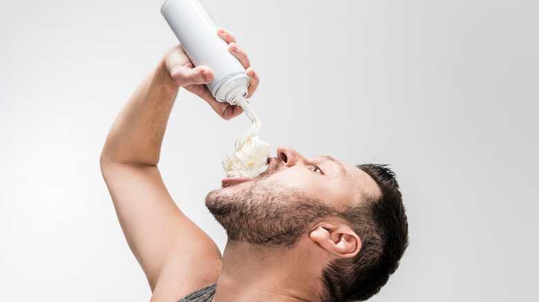 Man squirts whipped cream into mouth