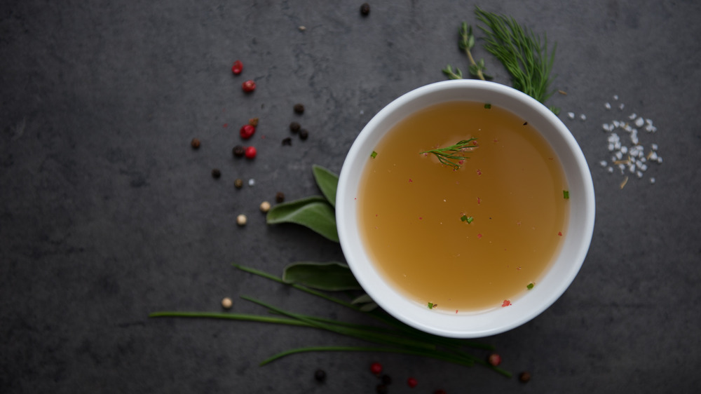 Chicken broth in a white bowl on a black background