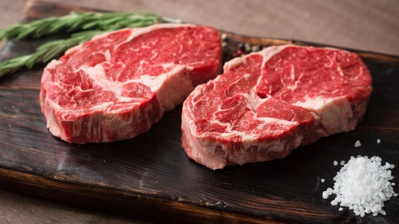 A pair of raw steaks on a wooden board