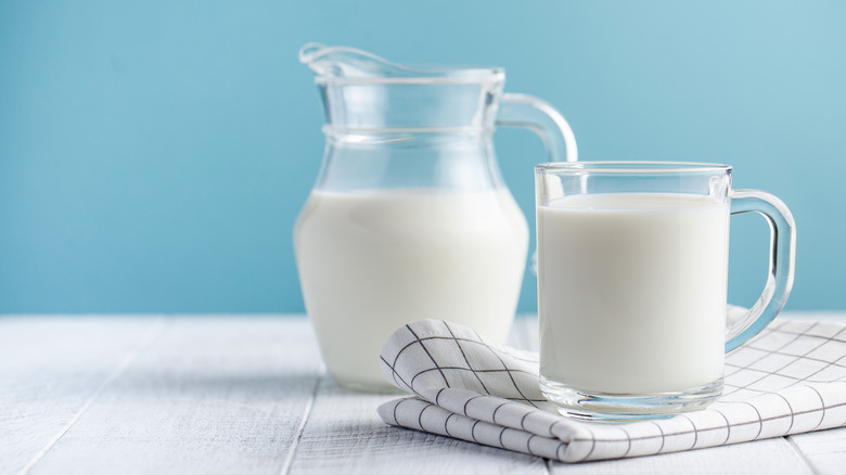 Two glass jugs of milk on blue background