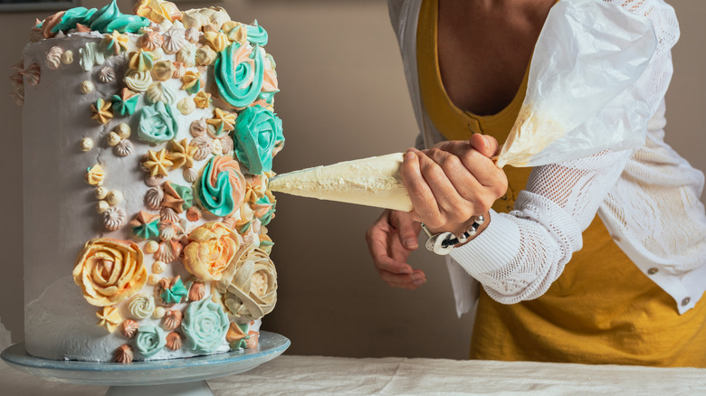 woman with pastry bag decorating cake