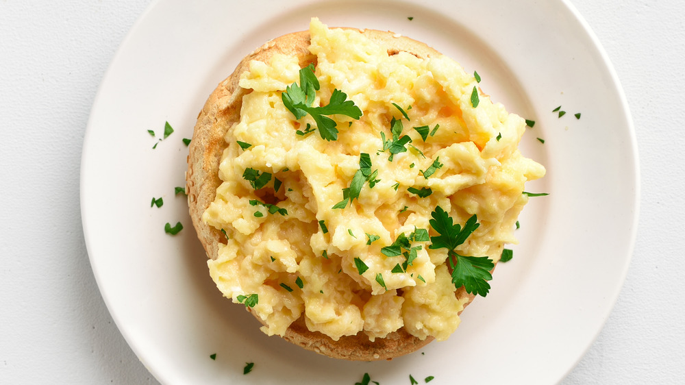 Scrambled eggs with herbs on half of a bagel