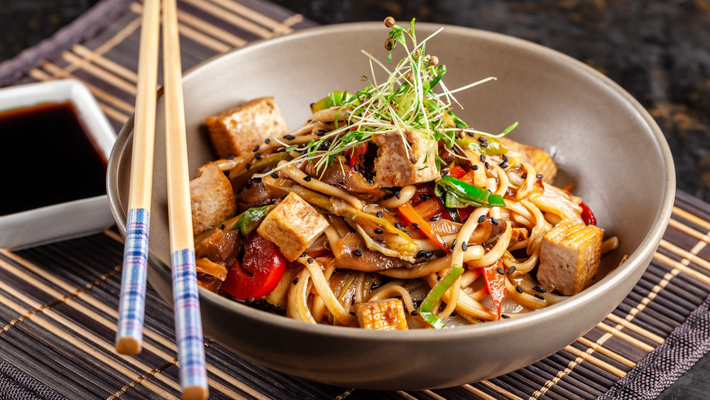 Tofu stir fry in bowl with chopsticks