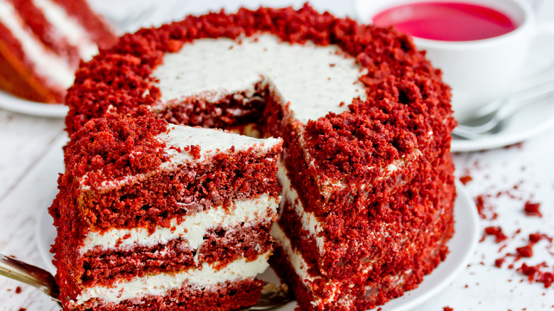 Whole red velvet layer cake with cut out slice